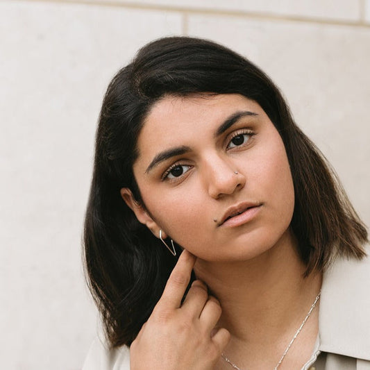 Model wearing sliver charm hoop earrings