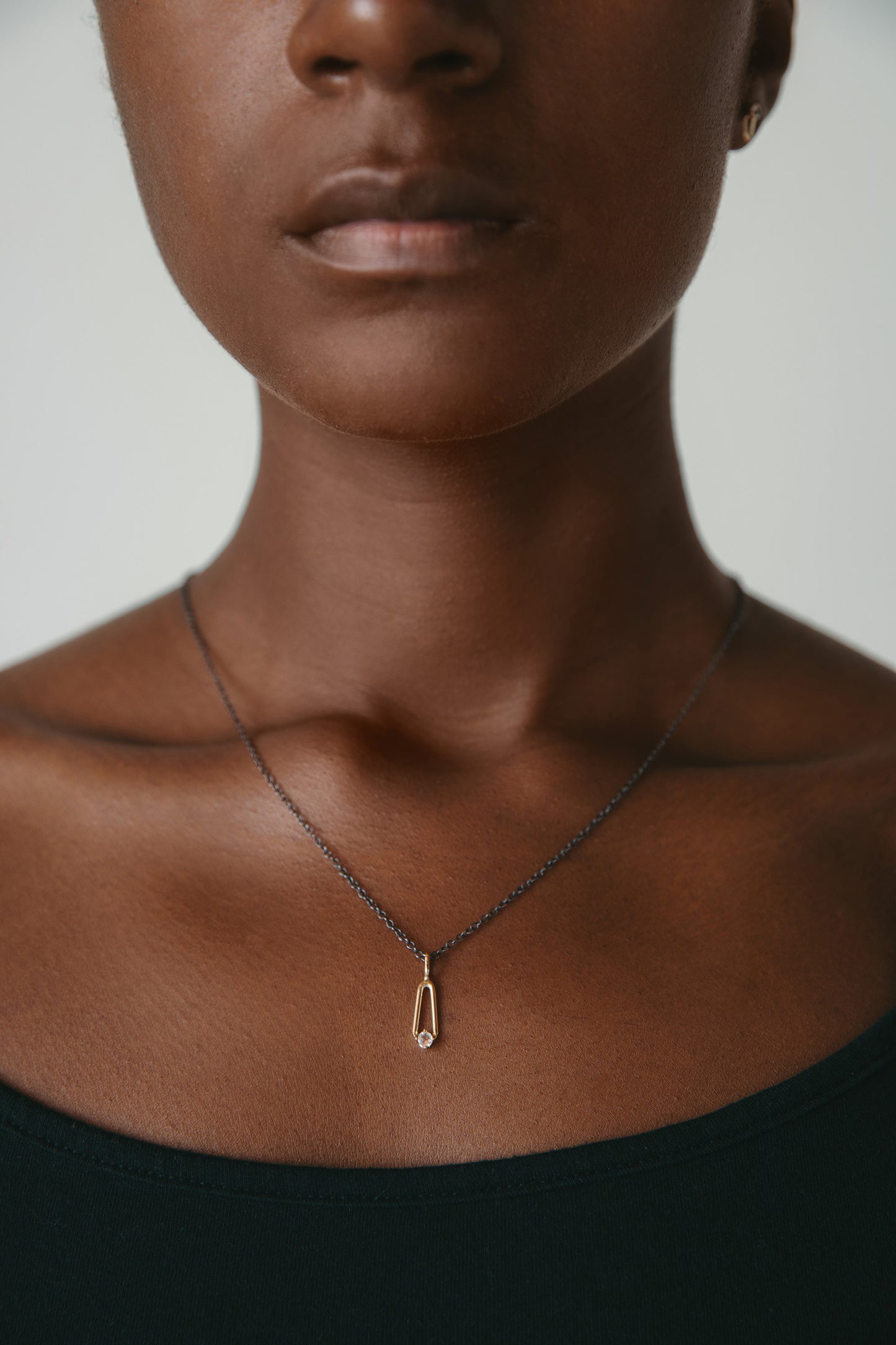 gold moonstone charm and black chain worn on model