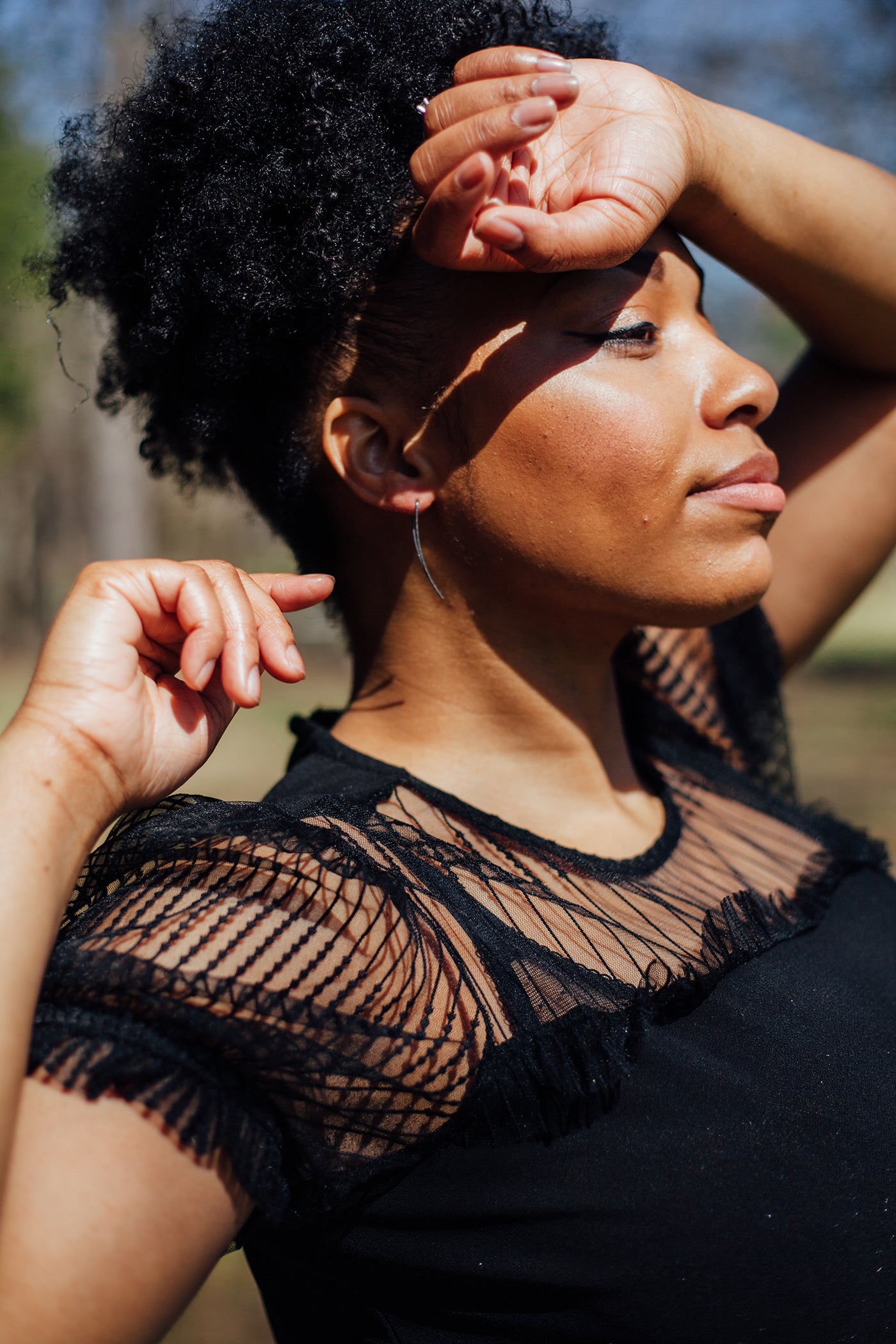 A model wearing silver curved bar threader hoops