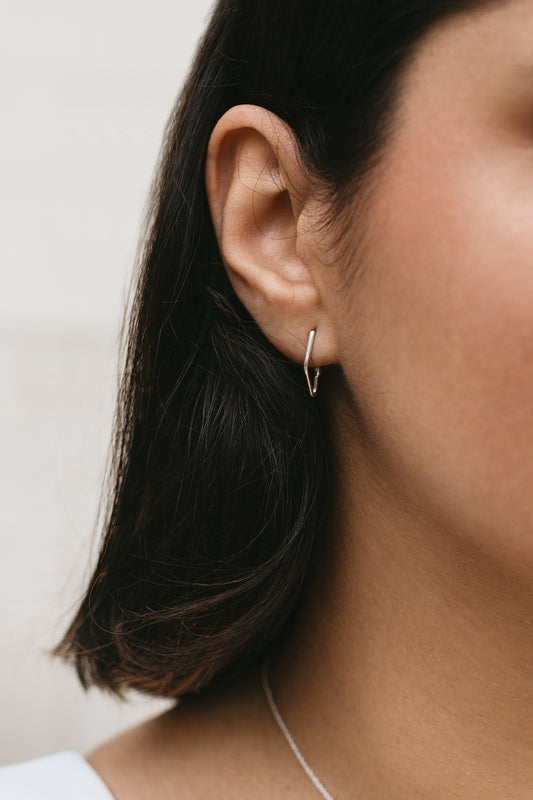 model wearing mini V-shaped charm hoop earrings