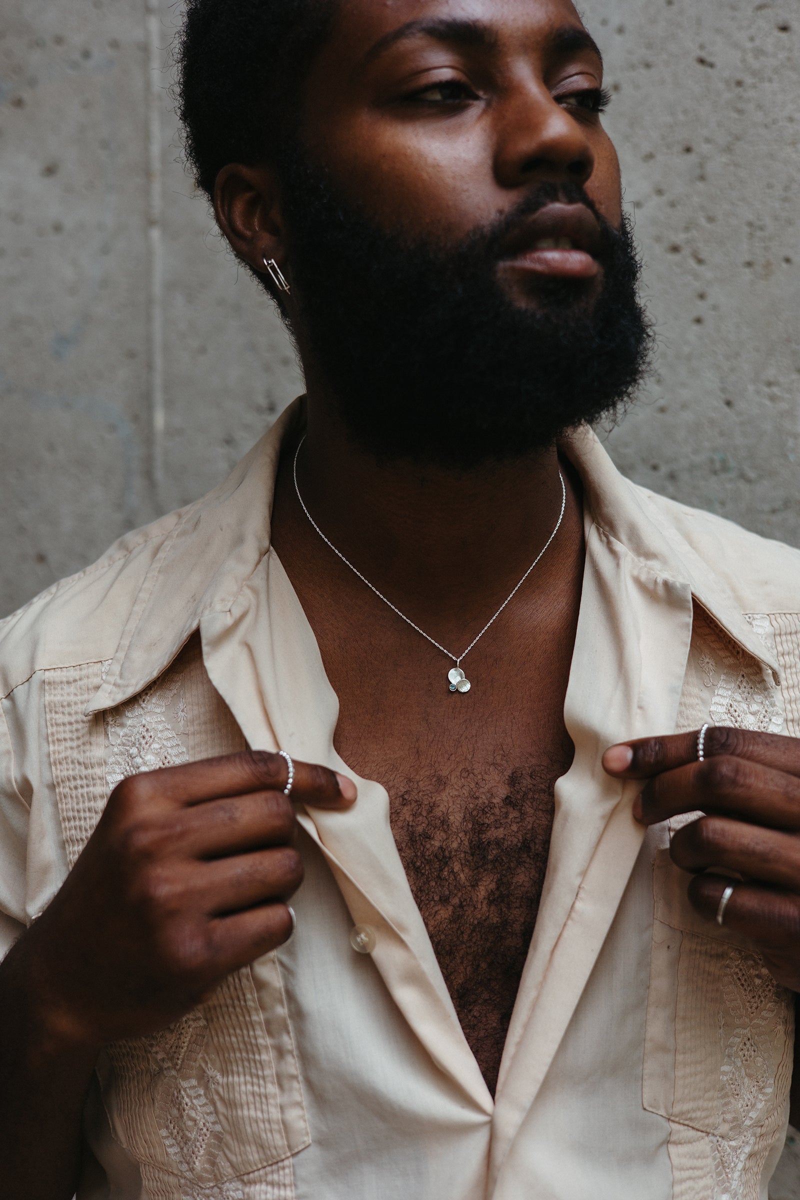 Model wearing concave disk pendant necklace with a blue sapphire
