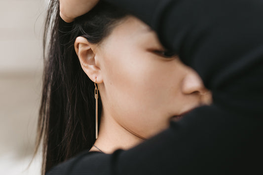 model wearing elongated silver angular bar earrings with 14k gold details