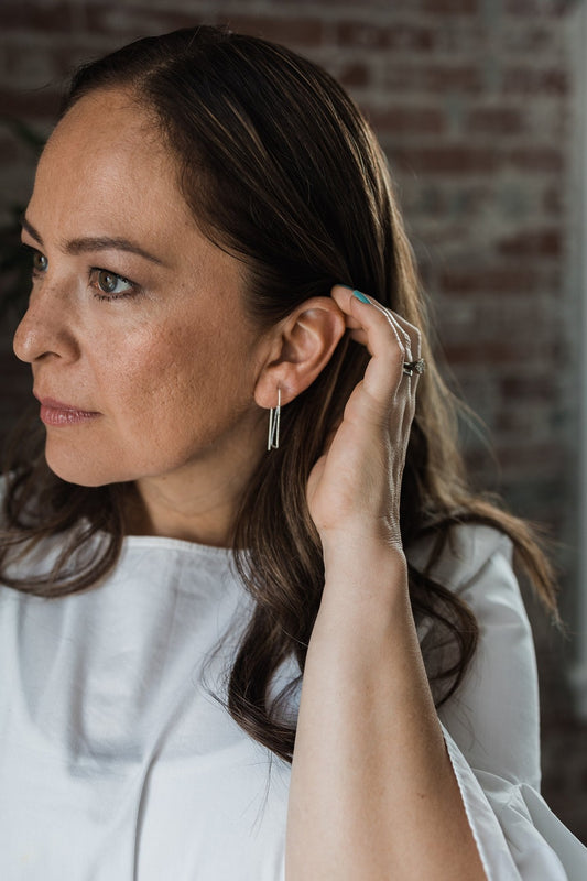 Model wearing silver rectangle pull through hoop earrings