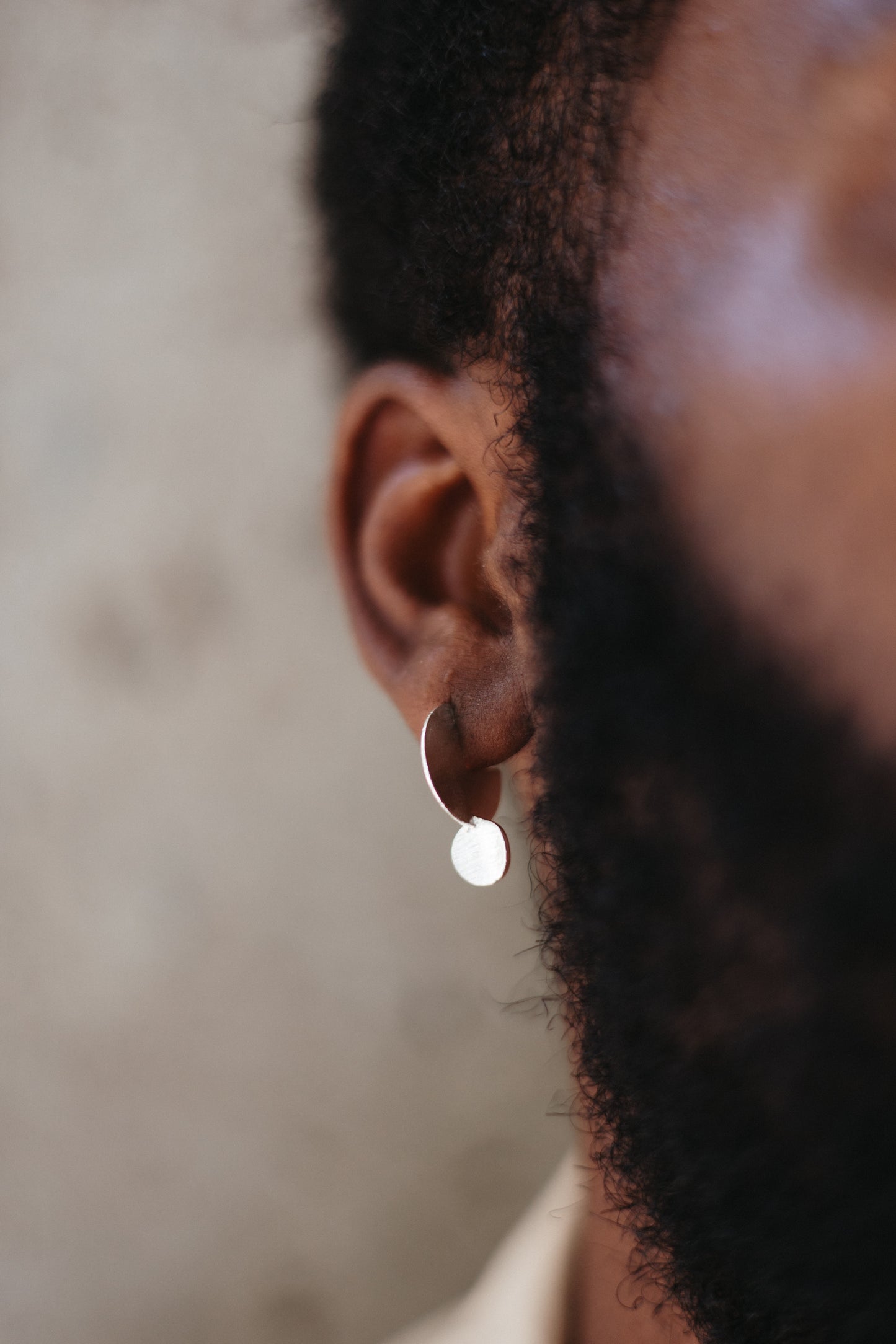 Textured silver drop disk stud earring on model