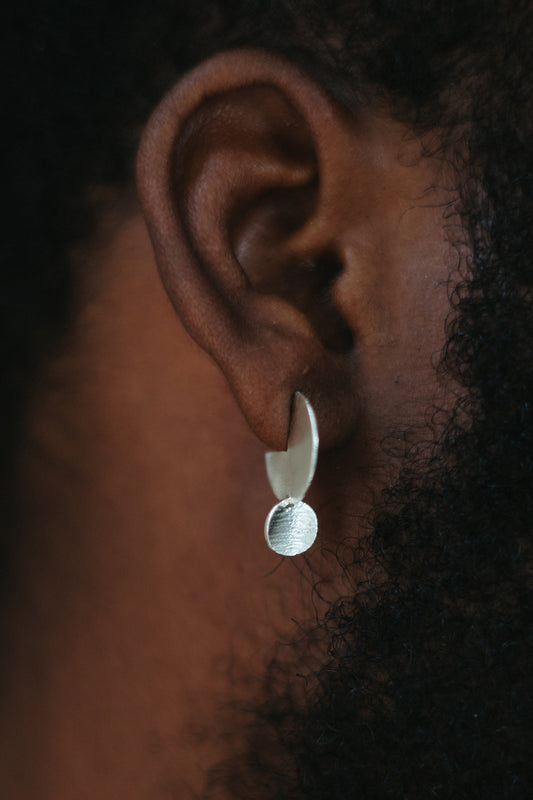 Textured silver drop disk stud earring on model
