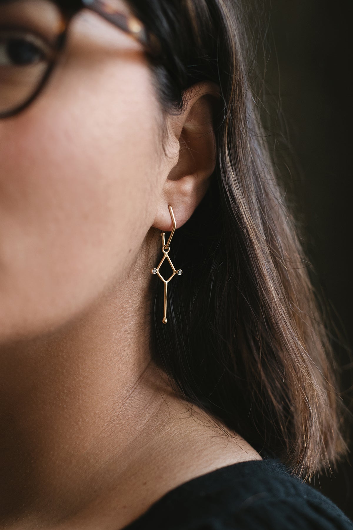 diamond-shaped earring with long bar drop and two black diamonds in 14K gold on model
