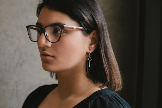 diamond-shaped earring with long bar drop and two black diamonds in 14K gold on model