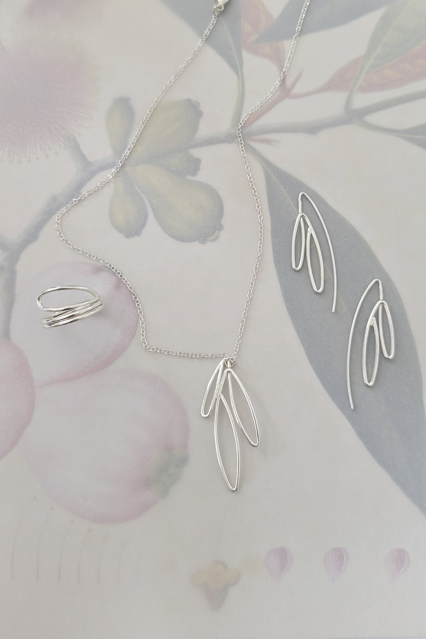 Silver necklace with leaf-shaped pendant on a soft floral background