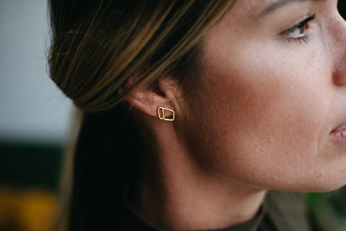14K gold open diamond shaped, asymmetrical outlined stud earrings worn on model