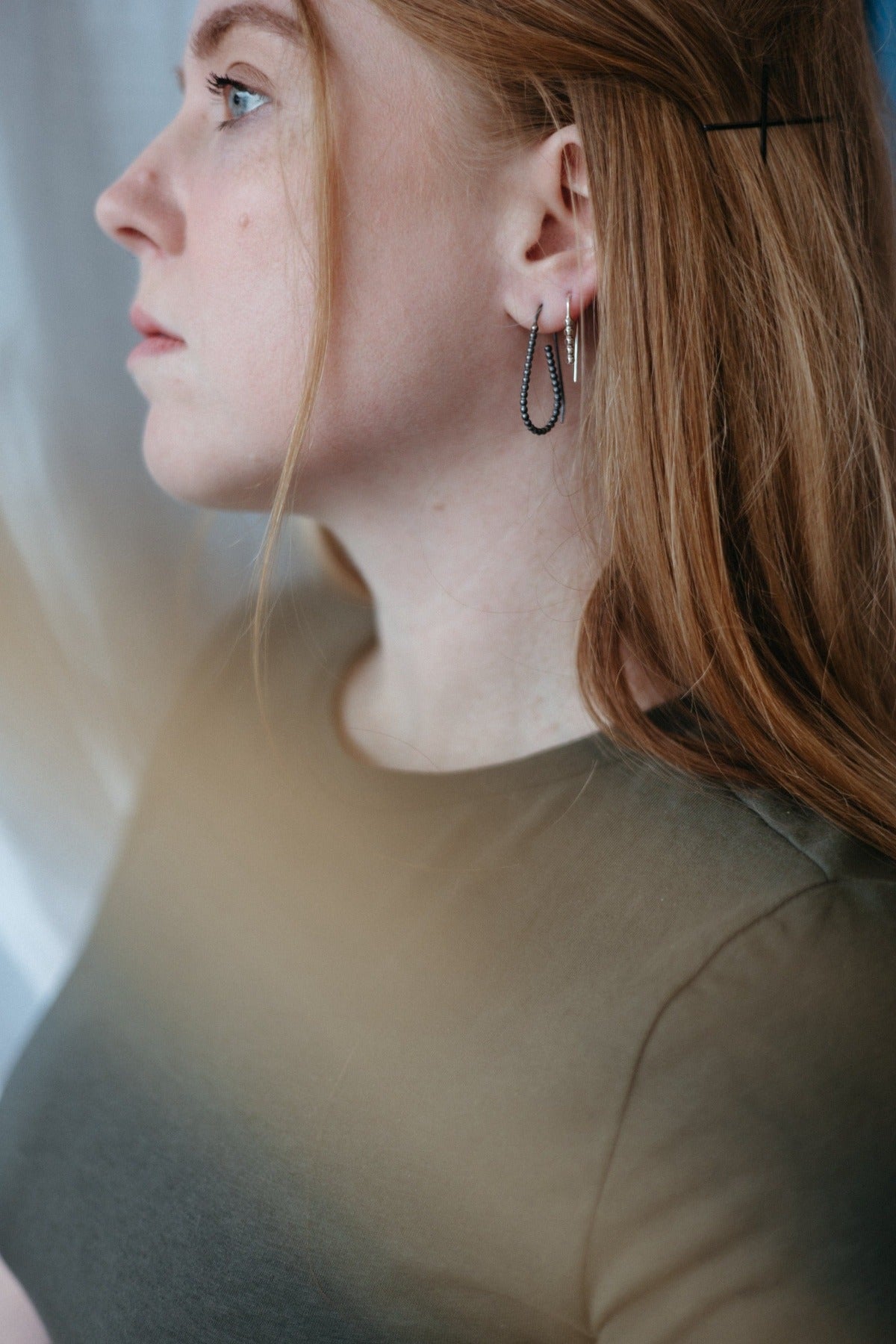 Silver and black beaded hoop earrings stack, worn on model