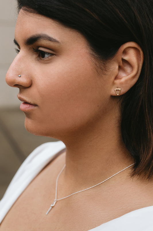 gold triangle stud earrings styled on model