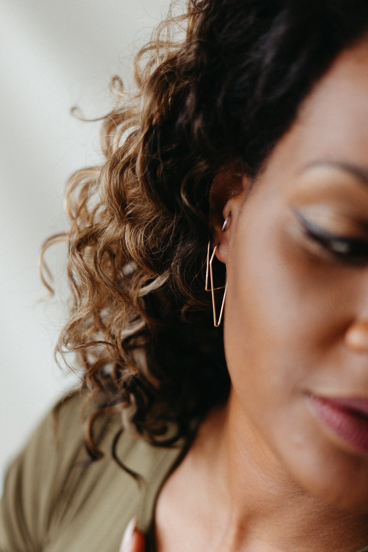 Gold triangle wire hoop earrings styled on model