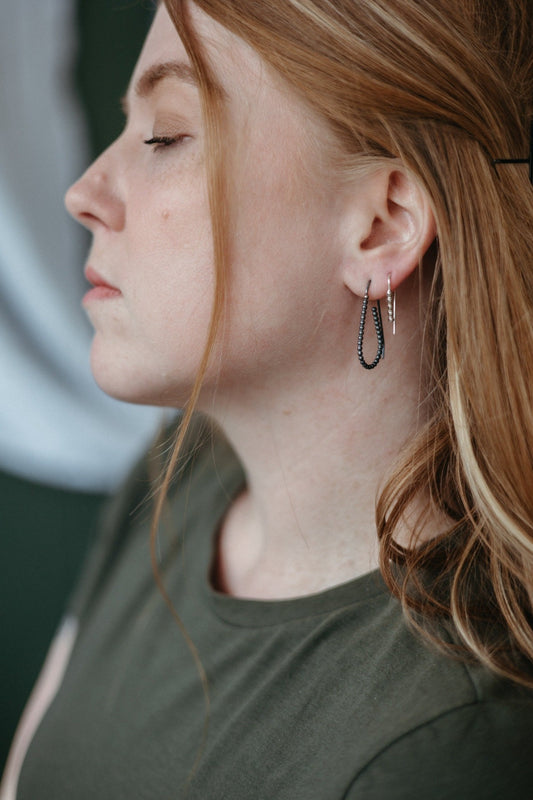 Model wearing silver and charcoal teardrop beaded wire hoops