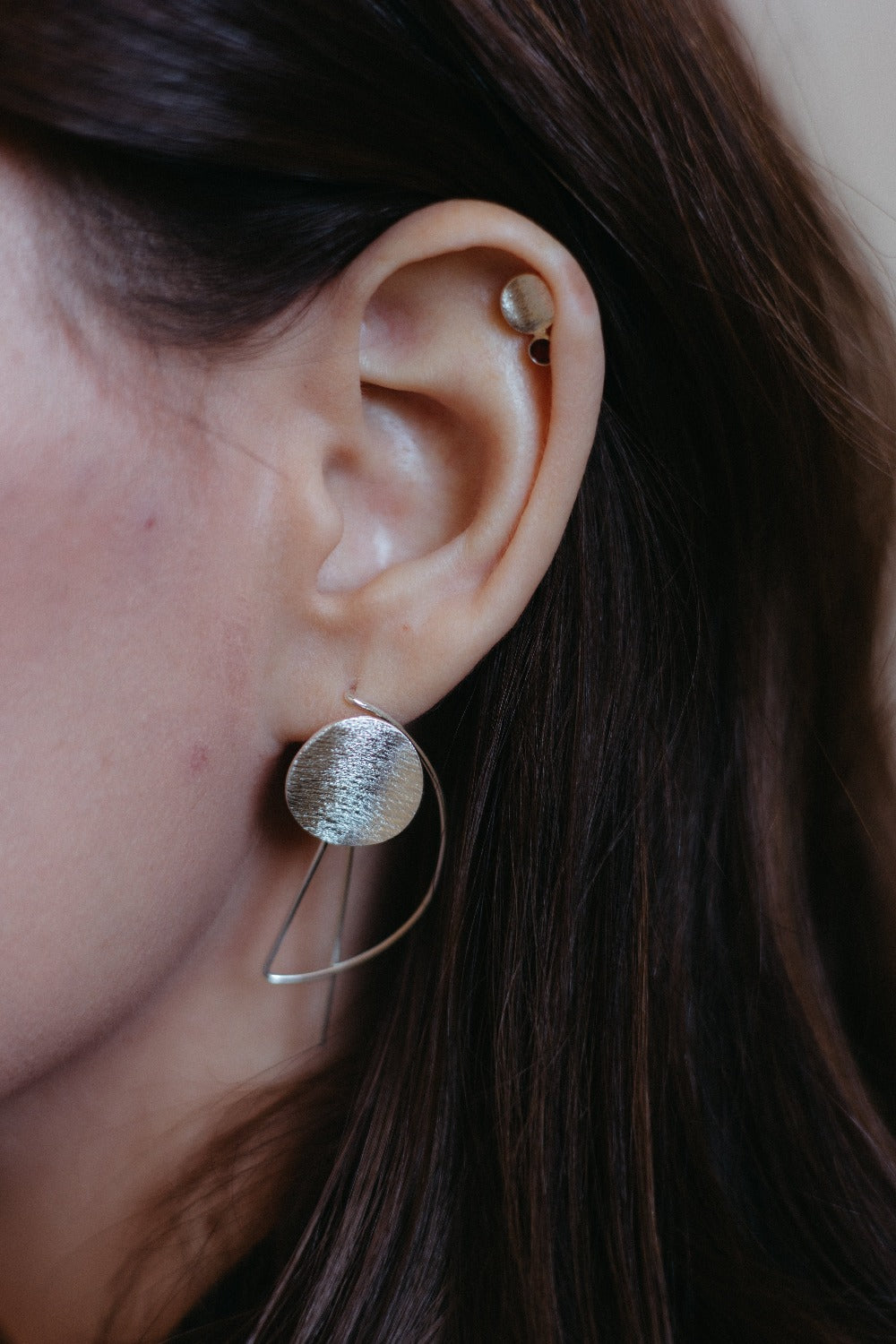 Small silver textured disk studs in a stack styled on model