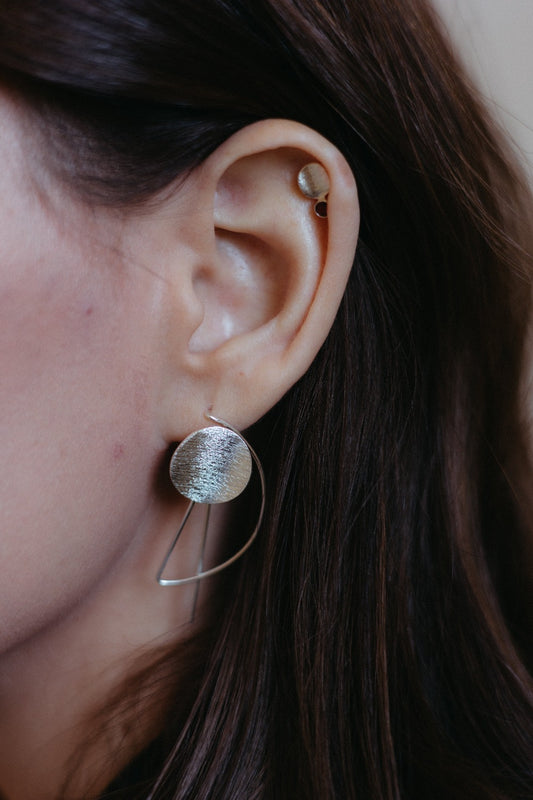 Small silver textured disk studs in a stack styled on model