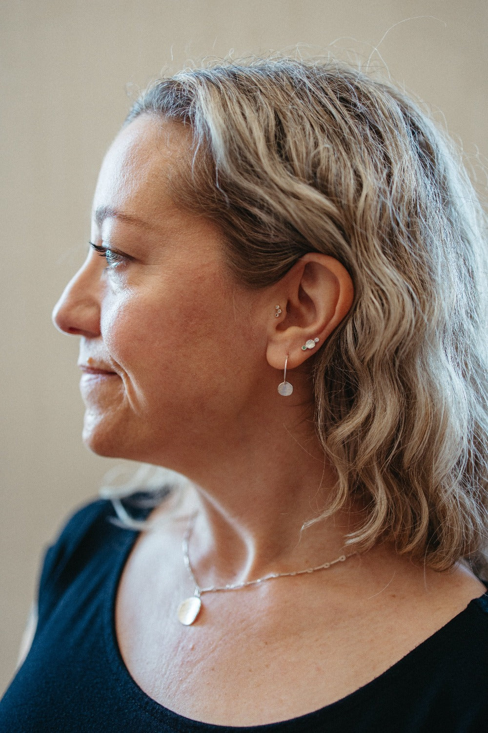 Circular drop disk stud earrings stacks on model