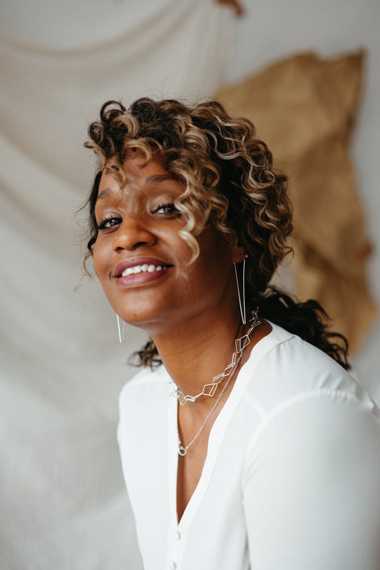 model wearing silver dagger hoops and open diamond necklaces