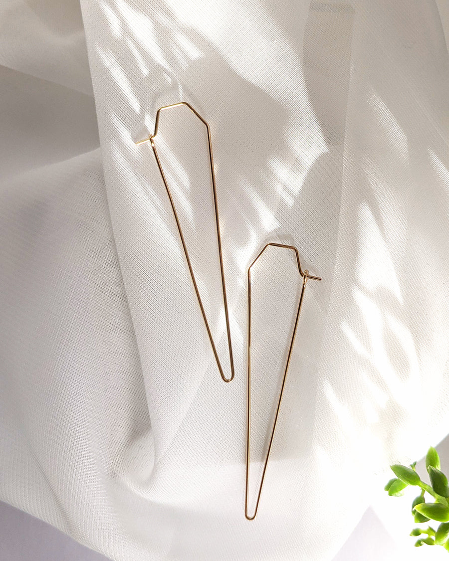 Gold triangle point hoop earrings on linen
