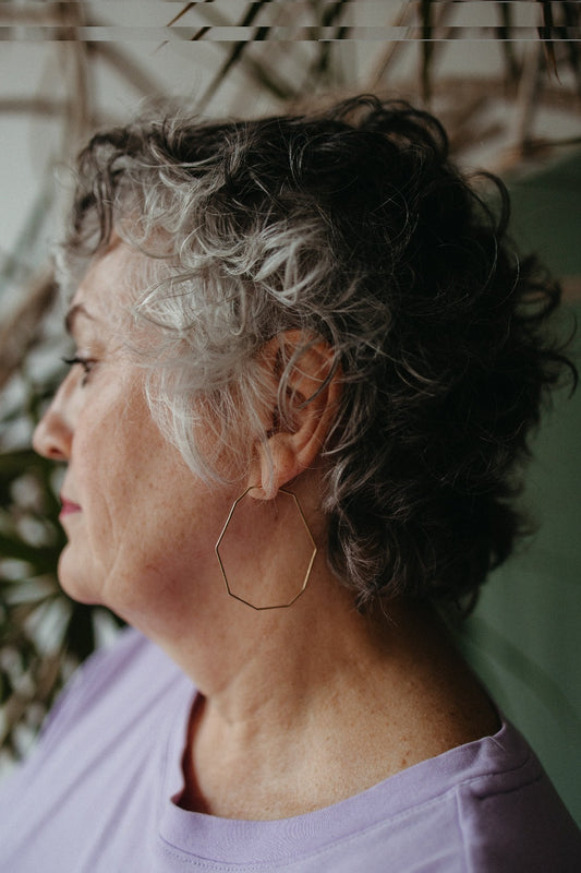 Model wearing Hammered gold decagon hoop earrings