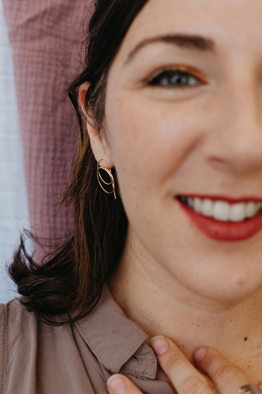 Model wearing gold spiral threader hoops