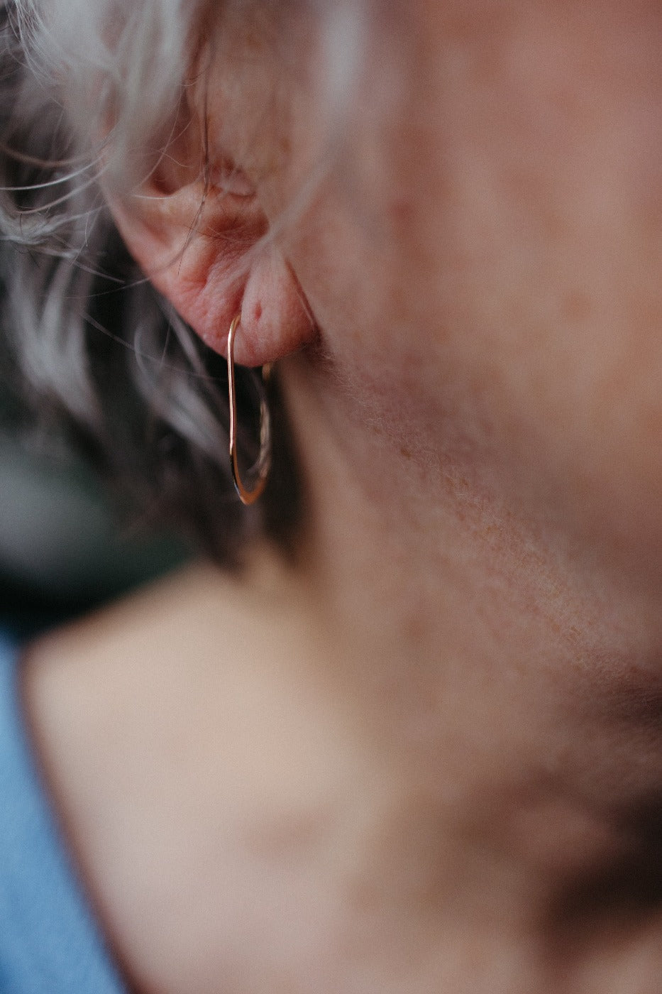 model wearing gold oval wire hoop earrings