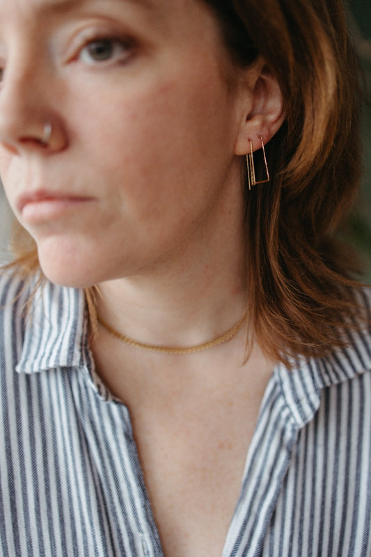 model wearing gold trapezoid wire earring stack