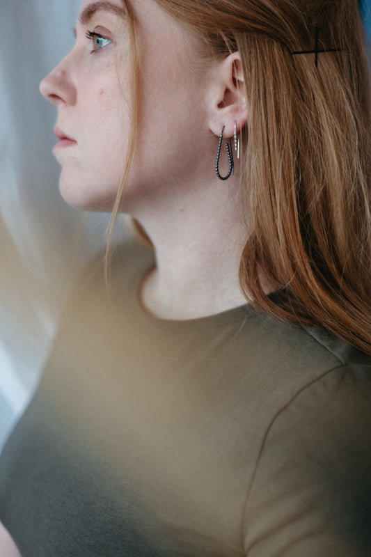 Silver and charcoal beaded wire hoop earring stack styled on model