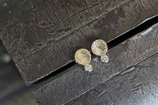 Gold stud earrings with tiny white diamonds on vise