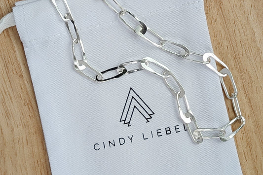 Silver oval paperclip chain on white branded jewelry pouch