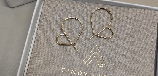 Gold heart hoop earrings on top of branded jewelry pouch