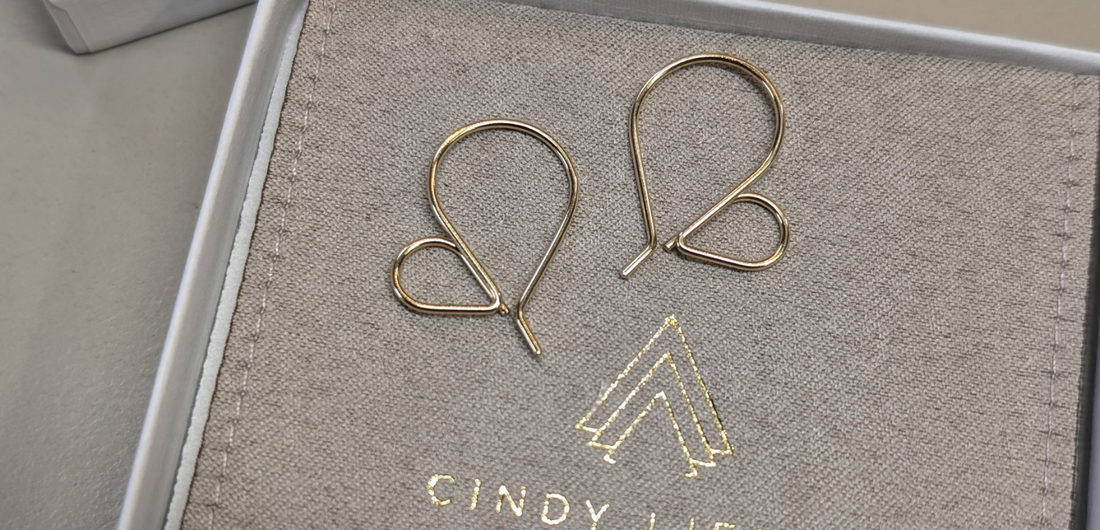 Gold heart hoop earrings on top of branded jewelry pouch