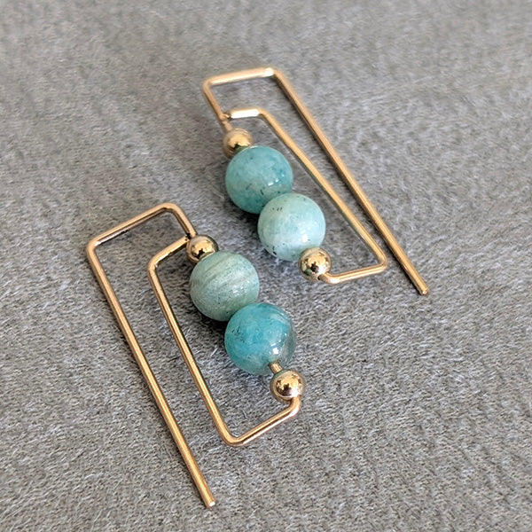 Gold earrings with Amazonite beads on a gray surface