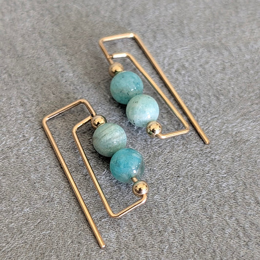 Gold earrings with Amazonite beads on a gray surface