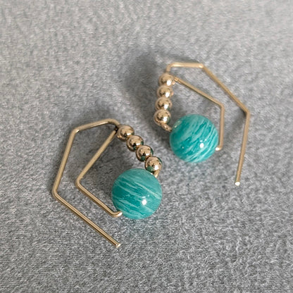 Gold and turquoise bead earrings on a gray surface