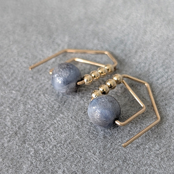 Gold and blue bead earrings on a gray textured surface