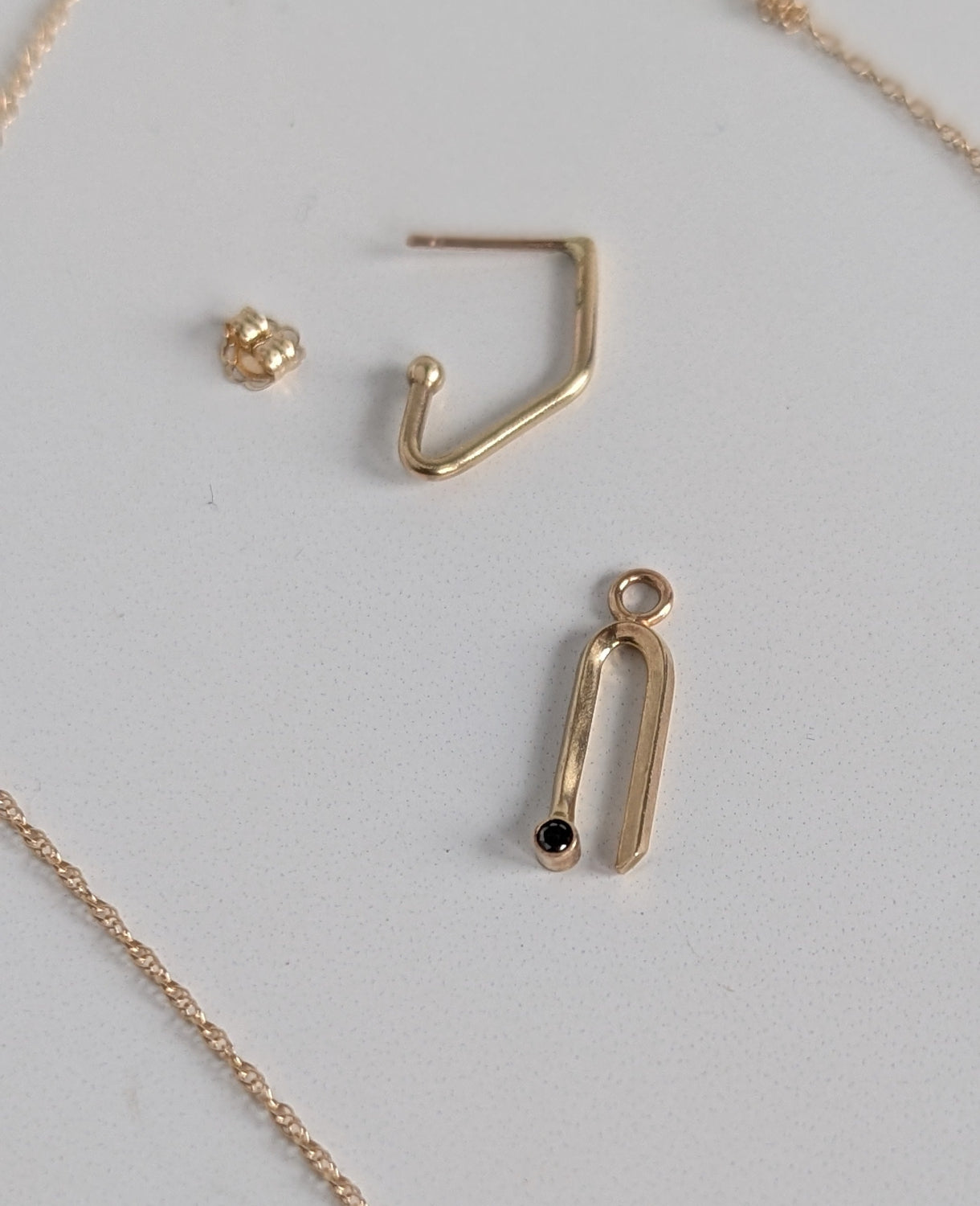 Gold necklace with pendant and earring on a light gray background