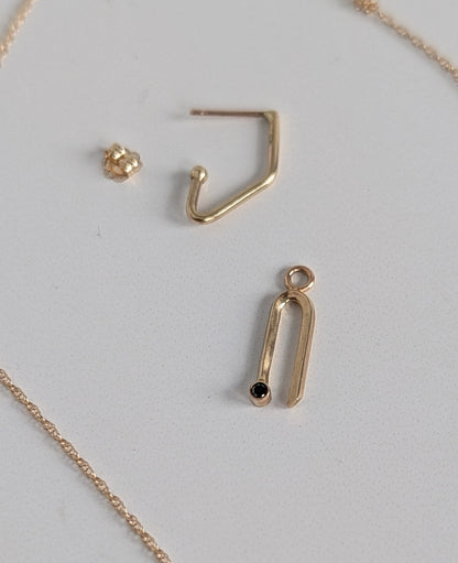 Gold necklace with pendant and earring on a light gray background