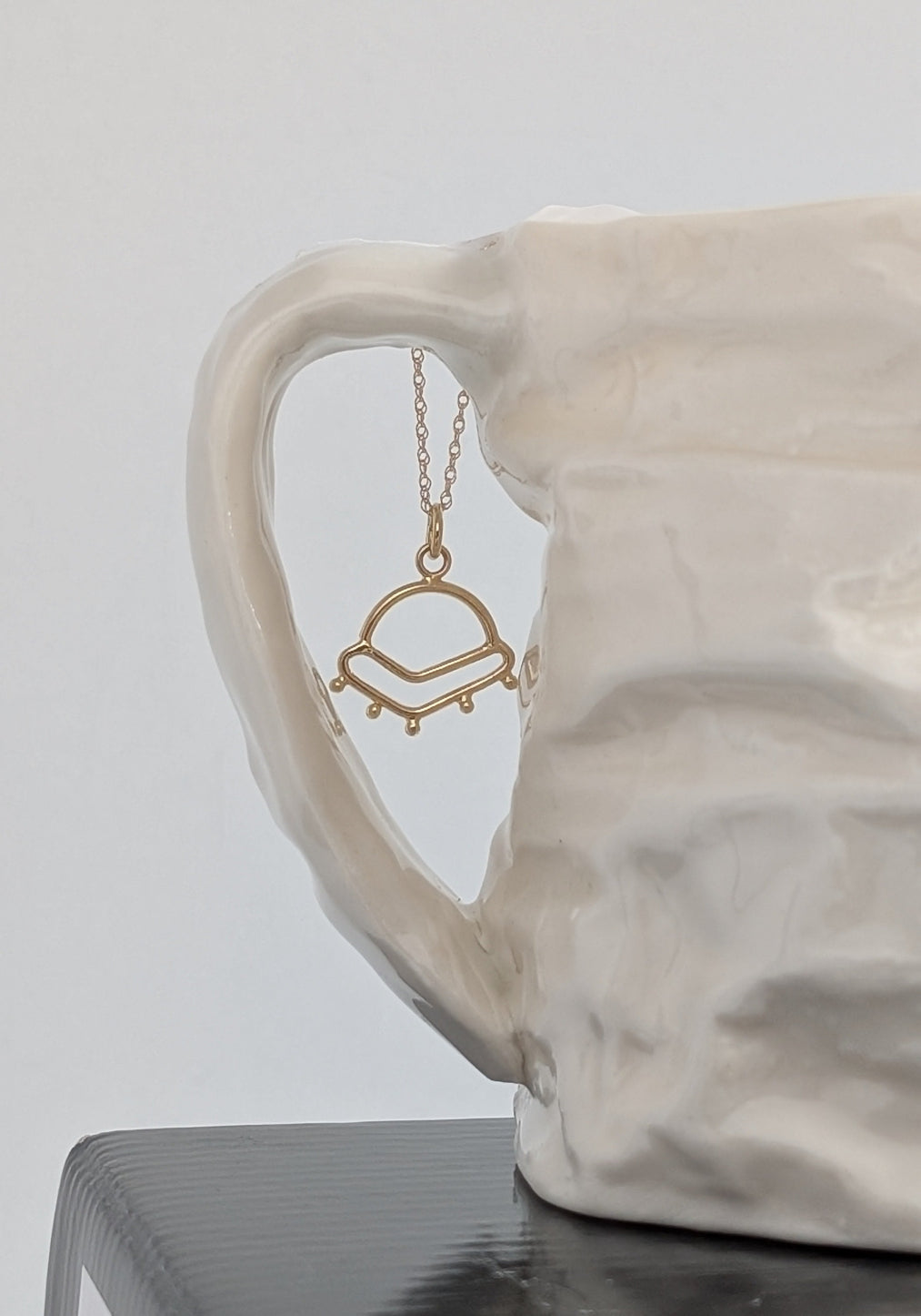 Sunrise inspired charm in 14K gold suspended from a 14K gold chain.