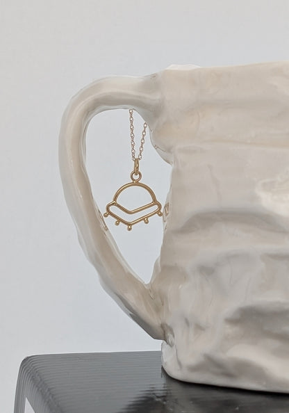 Sunrise inspired charm in 14K gold suspended from a 14K gold chain.