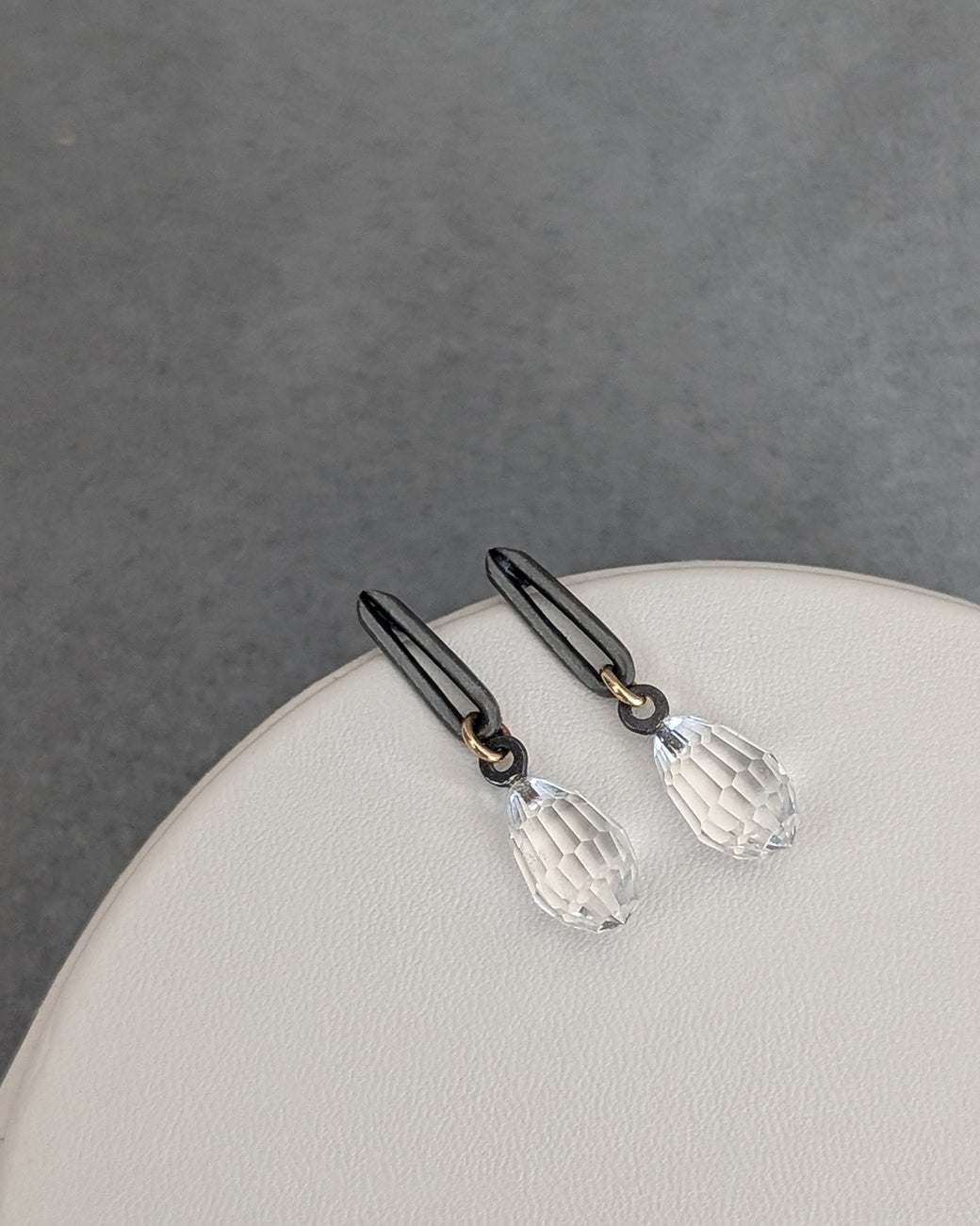 Pair of black hair clips with clear crystal pendants on a gray background