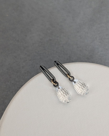 Pair of black hair clips with clear crystal pendants on a gray background