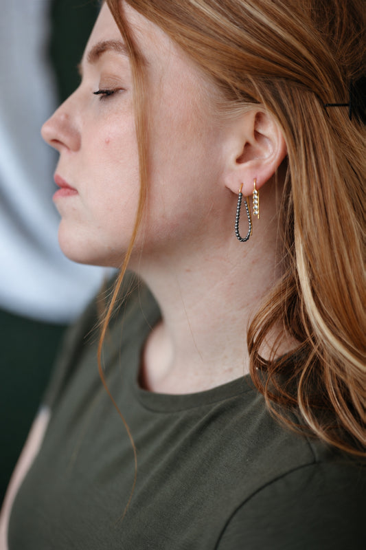 Gold and silver hoops stacked on model's ear wearing a green shirt.