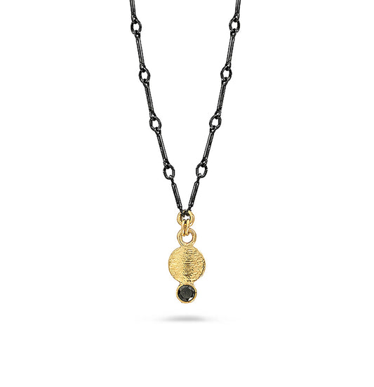 A gold pendant necklace and black diamond suspended on a black chain against a white background.