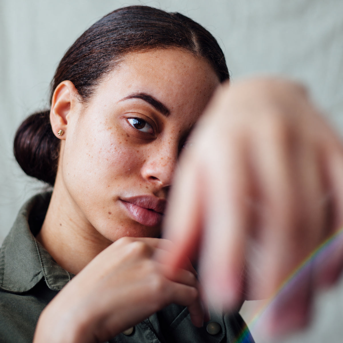 Tiny spiral 14K gold stud earrings worn on model with fabric draped in the background