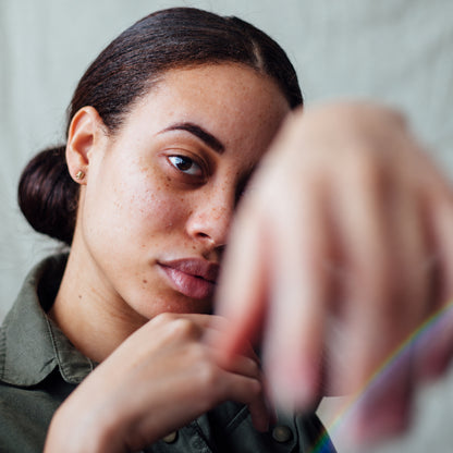 Tiny spiral 14K gold stud earrings worn on model with fabric draped in the background