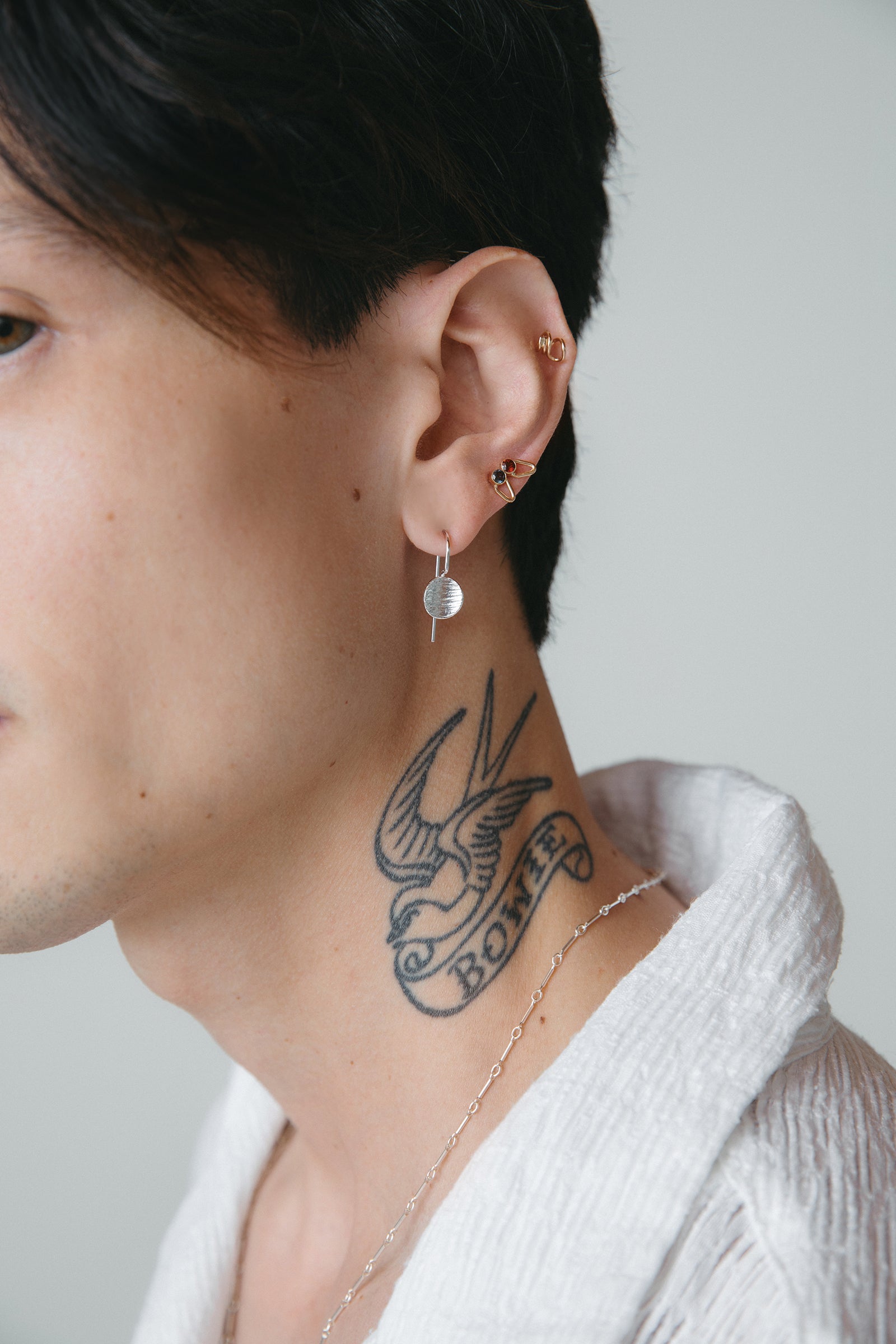 Silver drop textured disk earrings and gold birthstone studs styled on model