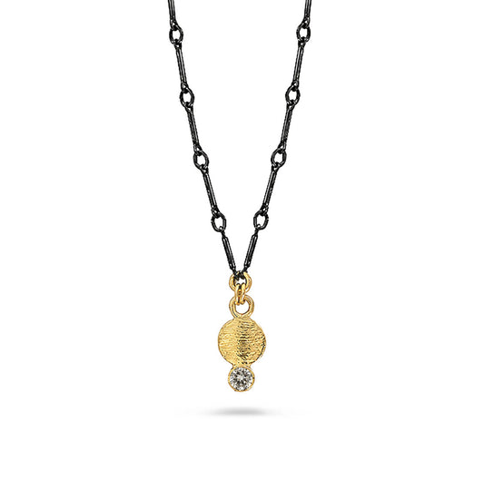 A gold pendant necklace and white diamond suspended on a black chain against a white background.